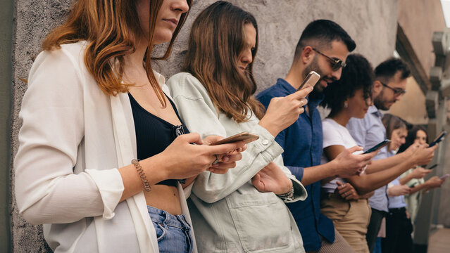 Multicultural group of people using smartphones standing outdoors