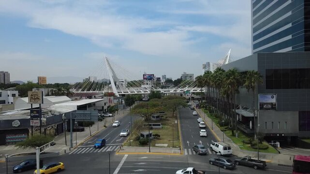 Aerial drone view of Matute Remus bridge in Guadalajara, Mexico, showcasing its iconic cable-stayed architecture and surrounding urban traffic. The shot highlights the modern infrastructure and dynami