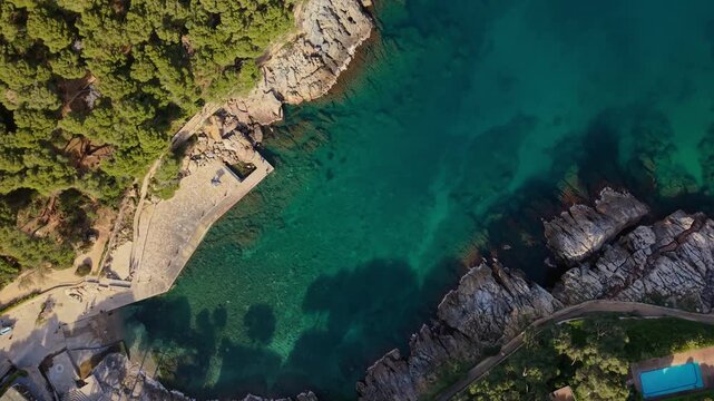 Top-down drone footage of the cove of Aiguafreda, located in Begur, Catalonia. Showcases the charming beach, historic houses, and the surrounding Mediterranean landscape. 