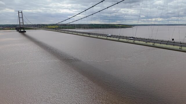 Aerial perspective of commuter traffic crossing the Humber Bridge above the wide brown silt waters of the estuary