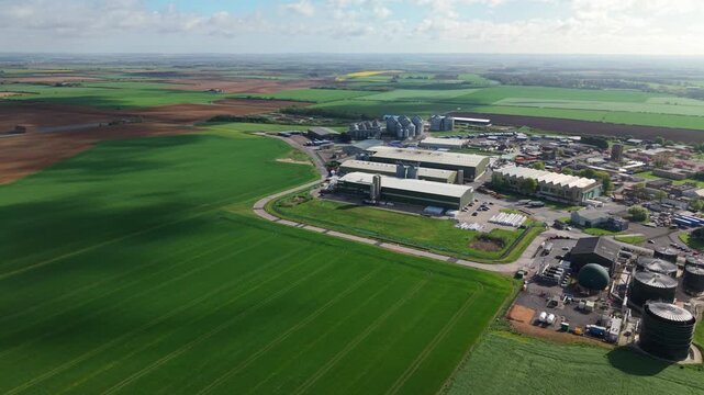 Birds eye view of geometric industrial farm warehouses and grain silos nestled in flat Lincolnshire arable land
