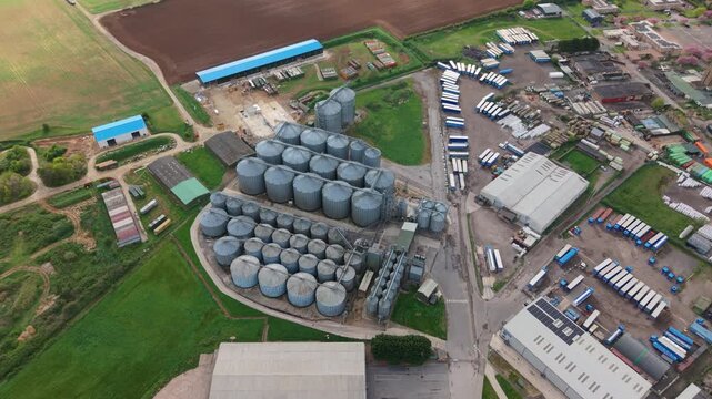 Aerial top down view of galvanized steel grain storage silos on a rural farm in the UK, agricultural infrastructure for cereal crop harvesting.