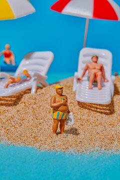 miniature man wearing striped shorts on the sand
