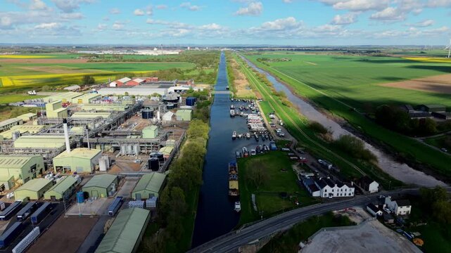 Drone shot of a large industrial chemical production plant and narrowboat marina under a green wind farm field