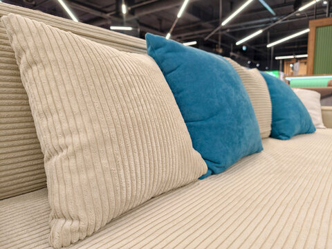 A stylish beige sofa with beige and blue pillows, available for sale in a furniture store