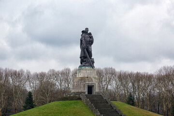 Obraz premium BERLIN, GERMANY - December 28, 2018: Monument to Soviet soldier holding at the hands German child at Soviet War Memorial in Treptower Park.