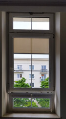 Obraz premium A window shows an outside view of a building and trees on a cloudy day in a city
