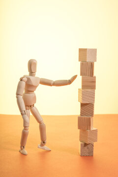 A man in a wooden figure is standing in front of a stack of wooden blocks