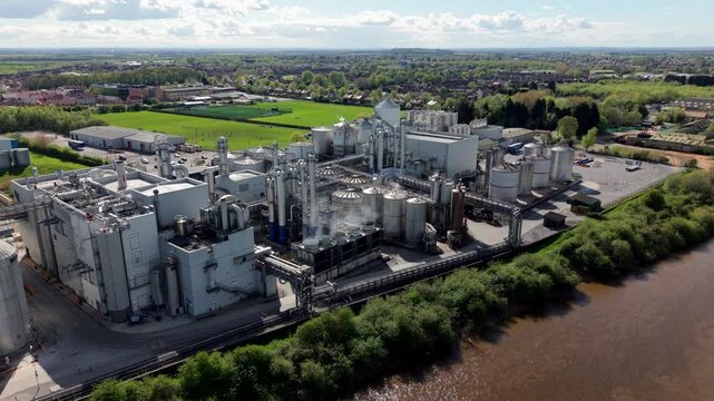 Aerial view of a massive industrial factory with manufacturing infrastructure and storage silos on the banks of the River Aire in Yorkshire