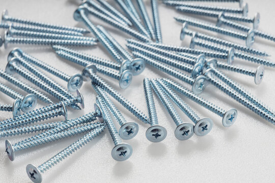 Metal zinc screws neatly arranged on white plastic background