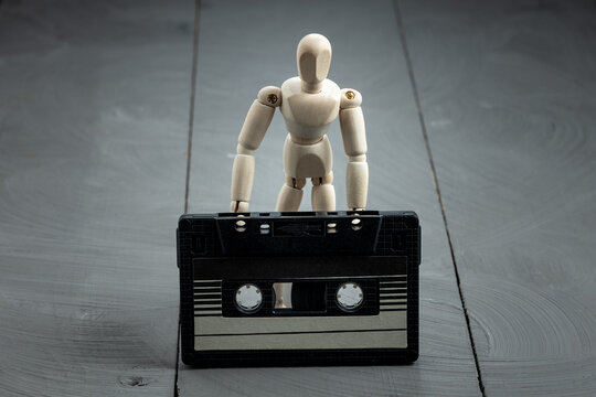 Artist mannequin beside retro cassette tape, analog memory and stillness theme