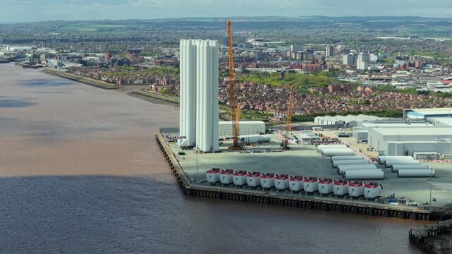 Drone shot of massive renewable energy wind turbine components and assembly quays on the River Humber Estuary near Hull