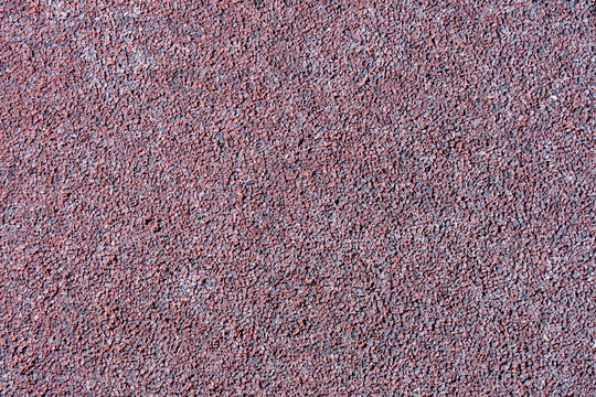 Textura de suelo de caucho reciclado para parque infantil en color rojo granate.