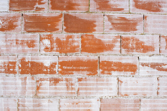 Textura de pared de ladrillos rojos con manchas de cemento blanco, fondo de construcci&oacute;n r&uacute;stico y desgastado.
