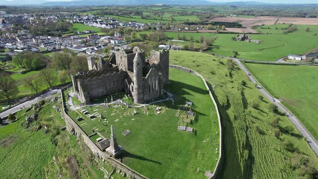 Aerial drone view of the Rock of Cashel, a historic medieval cathedral and fortress rising above the Irish countryside.