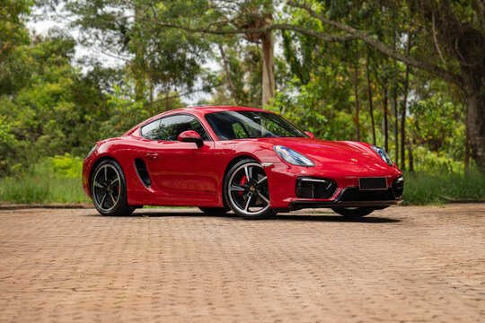Red porsche cayman gts front three quarters view near forest, High end luxury sports car outdoors