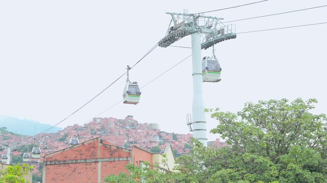 Medellin Metrocable gondola cabins moving above urban hillside neighborhoods, 4k video