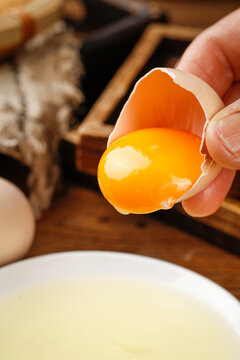 Fresh Farm Egg with Golden Yolk Cracked Open in Hand - Organic Cooking Ingredient