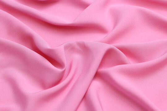 Premium pink 100% natural viscose fabric texture with elegant, soft drapes. Lightweight, breathable textile background in vibrant colors. Ideal for fashion design, apparel manufacturing, and sewing.
