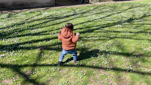 Toddler learning to walk on green grass