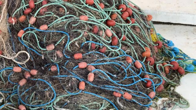 Fishing nets with blue ropes and red floats tangled together on rough surface background