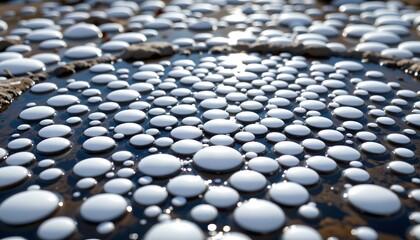 Obraz premium The image features a close up view of numerous smooth, white, rounded stones arranged on a surface, creating an abstract pattern