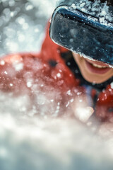 Fototapeta premium A person wears a bright red jacket and goggles, standing or sitting in a snowy landscape vertical frame