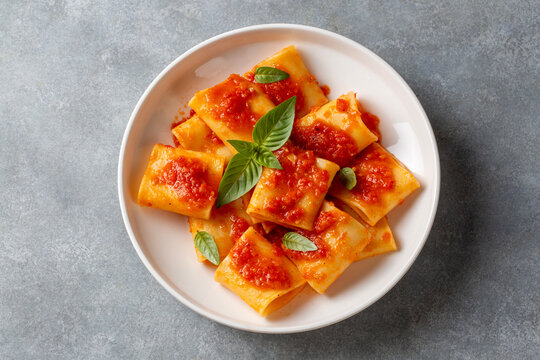 Paccheri allo Scarpariello Pasta with Tomato Sauce and Fresh Basil on a White Plate