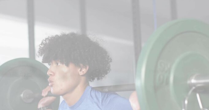 Man bracing core and inhaling, initiating back squat for fitness with barbell, green plates, rack