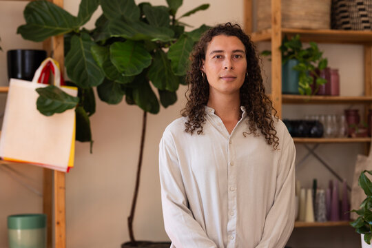 Fiddle leaf fig plant is anchoring boutique studio space with wooden shelves, jars, tote bag