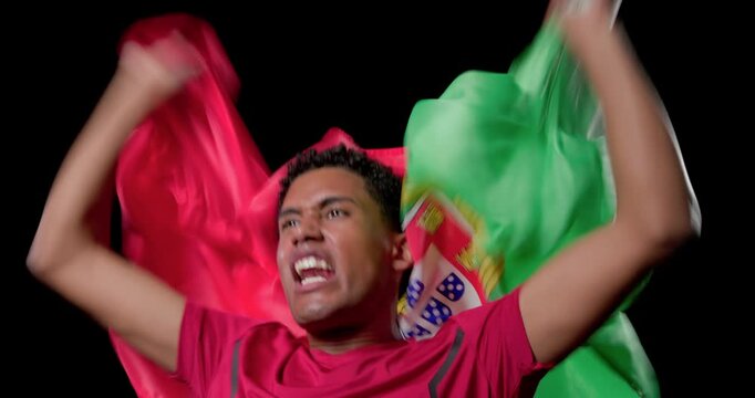 Adult African American male shouting and waving Portugal flag in red t-shirt at studio, celebrating