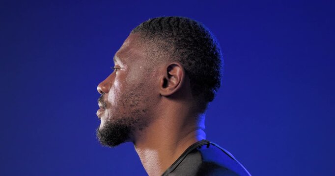 Man turning head toward camera on cue, highlighting sports shirt, jawline and blue backdrop