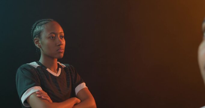 Vertical video: Panning camera in studio, two women in jerseys posing team shot holding soccer ball