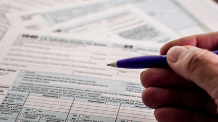 Obraz premium Hand holding pen preparing 1040 income tax form