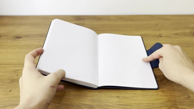 Horizontal close-up video of opening a blue notebook on a desk. 