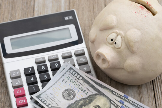Worried piggy bank with calculator and cash