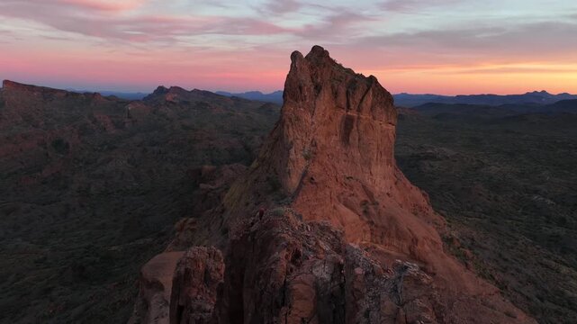 Aerial view of a majestic, rugged mountain peak with warm hues contrasting against the cool shadows of the surrounding landscape, Arizona, United States.