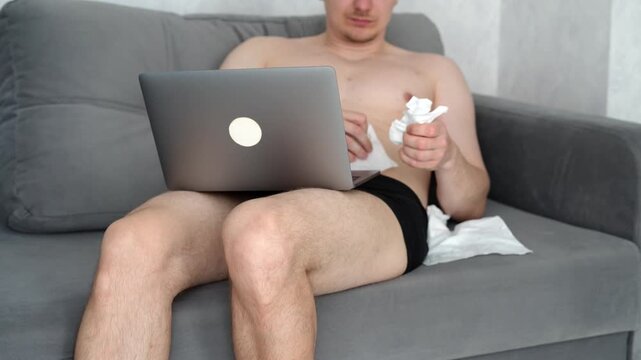 A man masturbates while watching erotic films while sitting on a couch in a room.
Achieving orgasm while watching pornographic content