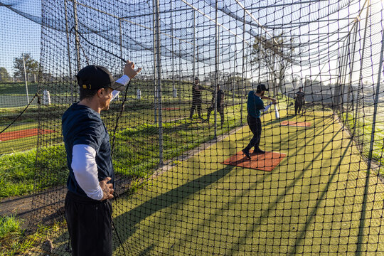 Coach signaling, batter swinging during baseball practice in cage, animated lines showing bat path