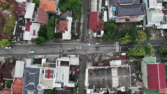 Aerial top down view of a busy city street intersection with houses and trees.
