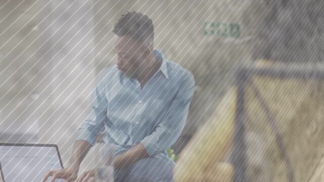 Man noticing yellow-jacket coworker, shifting from laptop to replying, leaning, gesturing in office