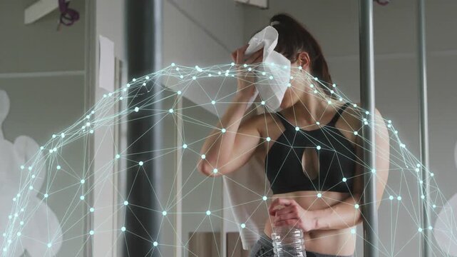 Woman dabbing sweat with towel after workout, holding water bottle, network dome overlaying torso