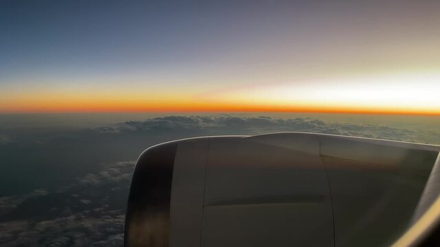 Flying above the clouds during sunset from aircraft window film, panning left wanderlust concept