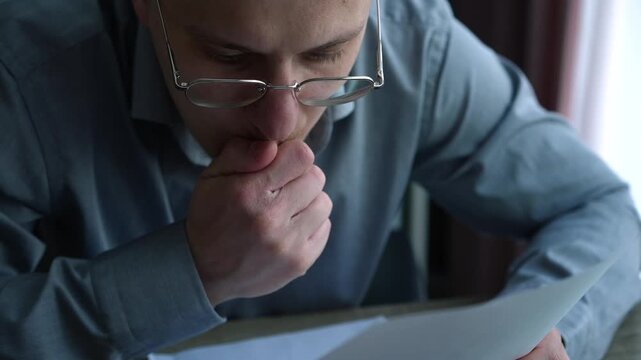 Close-up of a businessman reading documents at his desk in a modern office, concentrating on paper information and business workflow
