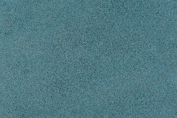 Fototapeta premium Blue rubber crumb surface texture from a sports or playground area, photographed full frame as a granular background with fine detail. Abstract turquoise textured background.