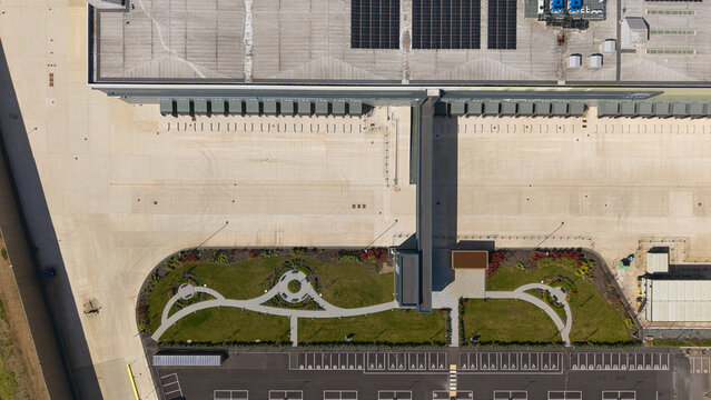 Aerial view of a supermarket distribution centre featuring loading bays, a landscaped garden area, and solar panels on the roof in Nailstone, Nuneaton, United Kingdom.