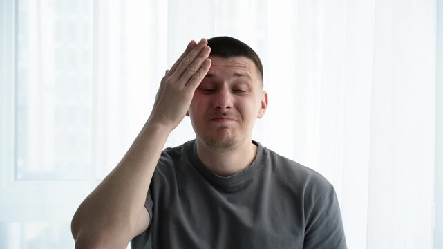 Close-up of a young man in a light room having a &ldquo;aha moment&rdquo;, smiling and pointing or gesturing in realization after remembering something important or funny.