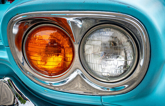 Detail of a Turquoise Vintage Car Headlight and Chrome Bumper