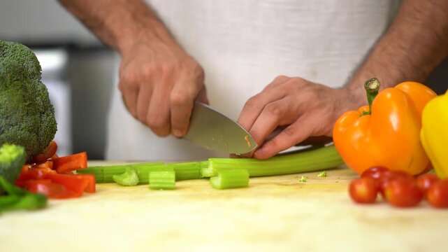 Slicing Celery on Cutting Board with Fresh Vegetables