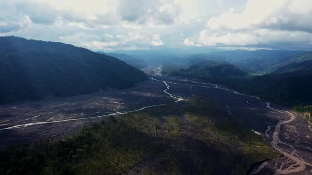 A meandering river has worn out a broad riverbed in the foothills of the Andes of Ecuador, trees are growing in the dirty river Upano due to the ashes of the volcano Sangay